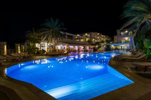 a swimming pool at night with chairs and buildings at Isida Hotel Agia Marina in Agia Marina Nea Kydonias