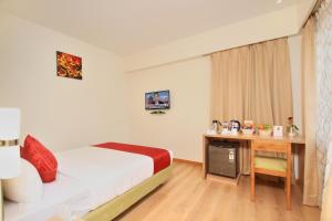 Habitación de hotel con cama, escritorio y cama en La Sara Regent, en Bangalore