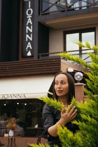 une femme debout devant un bâtiment dans l'établissement Ioanna Boutique Hotel, à Adler