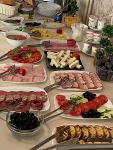 a table filled with different types of meats and vegetables at Park Luxury Rooms in Predeal