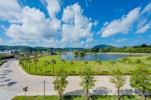 um parque com um lago e palmeiras em Wyndham Royal Lee Phuket em Nai Yang Beach