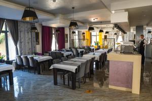 a restaurant with tables and chairs and a man standing at a counter at Hotel Vezir Palace in Travnik