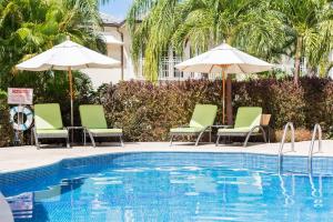 聖彼得的住宿－Shimmers, stunning, stylish West Coast Villa，一个带椅子和遮阳伞的游泳池