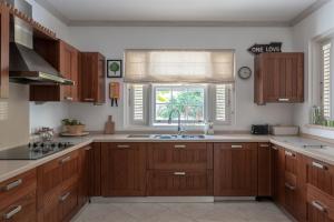 a kitchen with wooden cabinets and a sink and a window at Shimmers, stunning, stylish West Coast Villa in Saint Peter