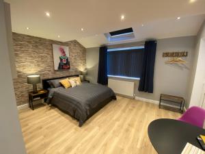 1 dormitorio con cama y pared de ladrillo en Modern Luxury 1 bed apartment with parking near Stansted Airport, en Stansted Mountfitchet