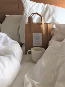 a paper bag and a cup on a bed at Savoy Hotel in Copenhagen