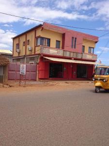 LE JAVA في Antsakomboena: شاحنة صفراء متوقفة أمام مبنى
