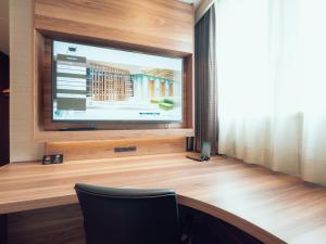 Habitación con TV de pantalla plana y escritorio de madera. en Henn na Hotel Sendai Kokubuncho, en Sendai