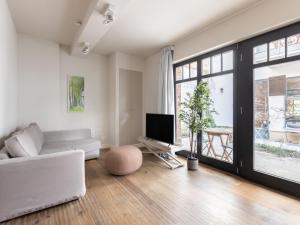 ein Wohnzimmer mit einem weißen Sofa und einem TV in der Unterkunft limehome Berlin Prenzlauer Allee - Digital Access in Berlin