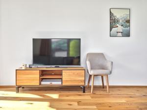 ein Wohnzimmer mit einem TV und einem Stuhl in der Unterkunft Panorama Lodge Auszeit 205 in Tauplitz
