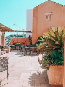 een patio met tafels, stoelen en planten bij Corte Di Nettuno - CDSHotels in Otranto