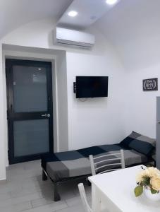 Antonio’s house في نابولي: غرفة بها أريكة وتلفزيون على الحائط