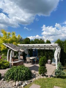 a white pergola with a table and a bench at Lemon home in Dziemiany