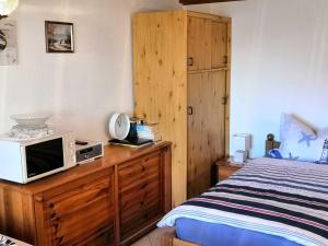 ein Schlafzimmer mit einem Bett und einer Mikrowelle auf einer Holzkommode in der Unterkunft Bungalow Poggendorf in Eldena