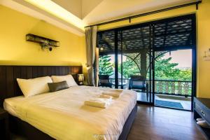 a bedroom with a large bed and a large window at Kongkarn Resort and Farmstay in Ban Pak Ngam