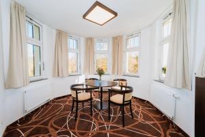 a dining room with a table and chairs and windows at Hotel Hubertus in Karlovy Vary