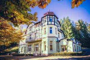 a large white building with a tower on top at Hotel Hubertus in Karlovy Vary