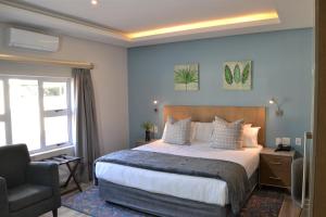 a bedroom with a bed and a chair and a window at Golf Course Boutique Guesthouse in Mount Edgecombe