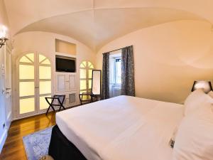 a bedroom with a large white bed and a tv at Hotel Balestri - WTB Hotels in Florence
