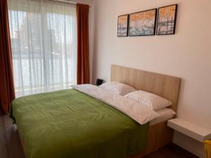 a bedroom with a bed with a green blanket and a window at Apartcentral in Baia Mare