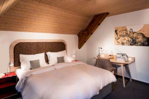 una camera da letto con un grande letto bianco e una scrivania di KONCEPT HOTEL Löie a Münsingen