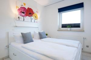 1 dormitorio con 2 camas blancas y ventana en Badeweg 4 Sandkorn 2, en Scharbeutz