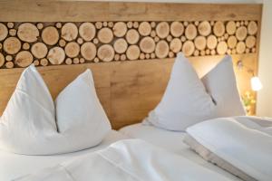 2 cuscini bianchi su un letto con testiera in legno di Hotel Zur Post a Bad Abbach