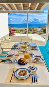 una mesa con platos de comida y vistas al océano en Thalia Myconian Suites en Kalafatis