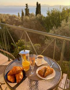 a table with croissants and cups of orange juice and coffee at Nissaki Jonas Apartment in Nisakion +6 photos