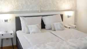 uma cama com lençóis brancos e almofadas num quarto em Rosenwinkel Appartement im OG em Halberstadt