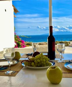 un tavolo con un piatto di uva e una bottiglia di vino di Thalia Myconian Suites a Kalafatis