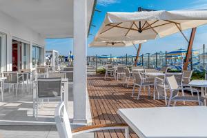 a patio with tables and chairs and an umbrella at Hotel City in Milano Marittima