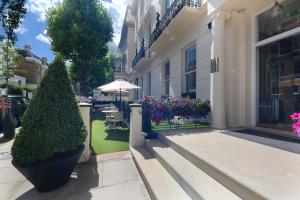 un bâtiment avec deux grandes plantes sur le trottoir dans l'établissement Park Grand London Lancaster Gate, à Londres