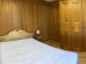 レ・セジーにあるAppartement Les Saisies, 2 pièces, 4 personnes - FR-1-293-235の白いベッドと木製の壁が備わるベッドルーム1室が備わります。