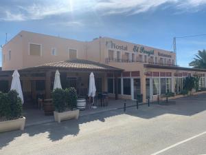 a hotel with tables and umbrellas in front of a building at Hostal El Perejil in Cuevas del Almanzora