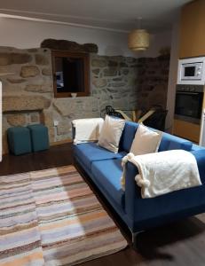 a blue couch in a living room with a stone wall at Casa do Eirô in Pinheiro