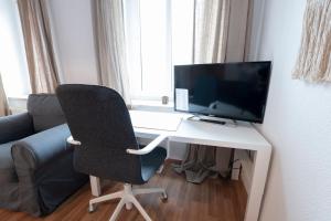 uma secretária de computador com um monitor e uma cadeira em Lutherviertel-Apartment mit 2 SZ in Uni-Nähe em Chemnitz
