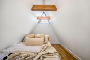 a bed in the corner of a room with white walls at Unique A-frame Tiny House in Houston Central in Houston