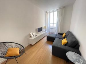 ein Wohnzimmer mit einem schwarzen Sofa und einem TV in der Unterkunft Appartamento Gasparo da Salò in Salò