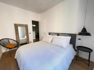 Schlafzimmer mit einem weißen Bett und einem Spiegel in der Unterkunft Appartamento Gasparo da Salò in Salò