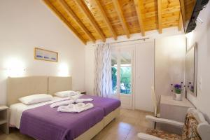 a bedroom with a purple bed with towels on it at VOULA STUDIOS in Skiathos