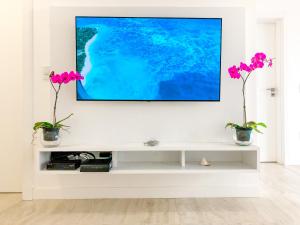 uma sala de estar com televisão numa parede branca em Casa com 4 suítes em Jurerê Internacional em Florianópolis