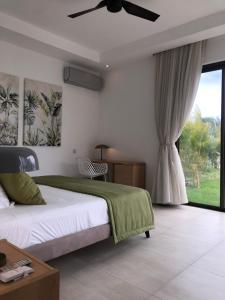 1 dormitorio con 1 cama y ventilador de techo en L'Idéale : Villa neuve et cosy, piscine privative et chauffée, en Cap Malheureux