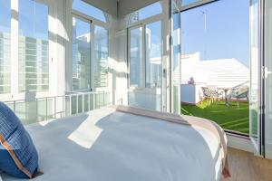 Cama en habitación con ventanas grandes en LS9- La Palmera Luxury by Valcambre en Sevilla