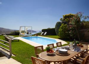 a table and chairs next to a swimming pool at Heliades Villas in Gavrio