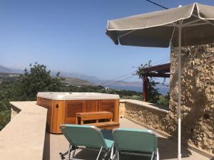 a patio with two chairs and an umbrella at Guesthouse Arkadi Spa in Atsipopoulo