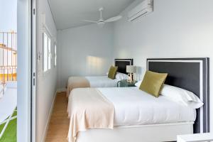 een witte slaapkamer met twee bedden en een raam bij LS9- La Palmera Luxury by Valcambre in Sevilla +91 foto's