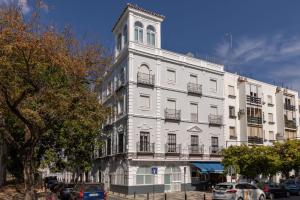 un bâtiment blanc avec une tour d'horloge dans une rue dans l'établissement LS9- La Palmera Luxury by Valcambre, à Séville