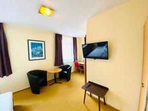 a room with chairs and a flat screen tv at Hotel Grimm in Kassel