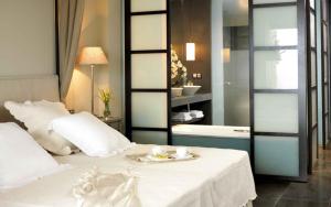 1 dormitorio con cama blanca y baño en Asia Gardens Hotel & Thai Spa, a Royal Hideaway Hotel en Finestrat